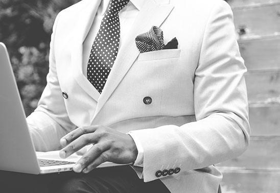 S képen egy elegáns üzletember látható, laptoppal a kezében.